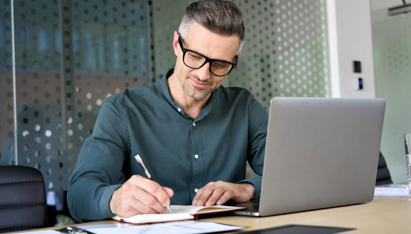 High-income professional in the UAE reviewing financial notes at a desk with a laptop