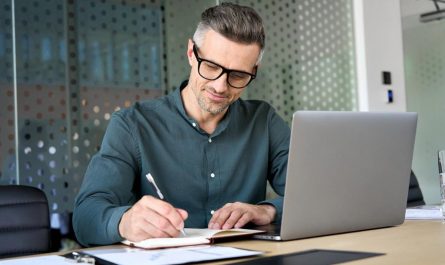 High-income professional in the UAE reviewing financial notes at a desk with a laptop